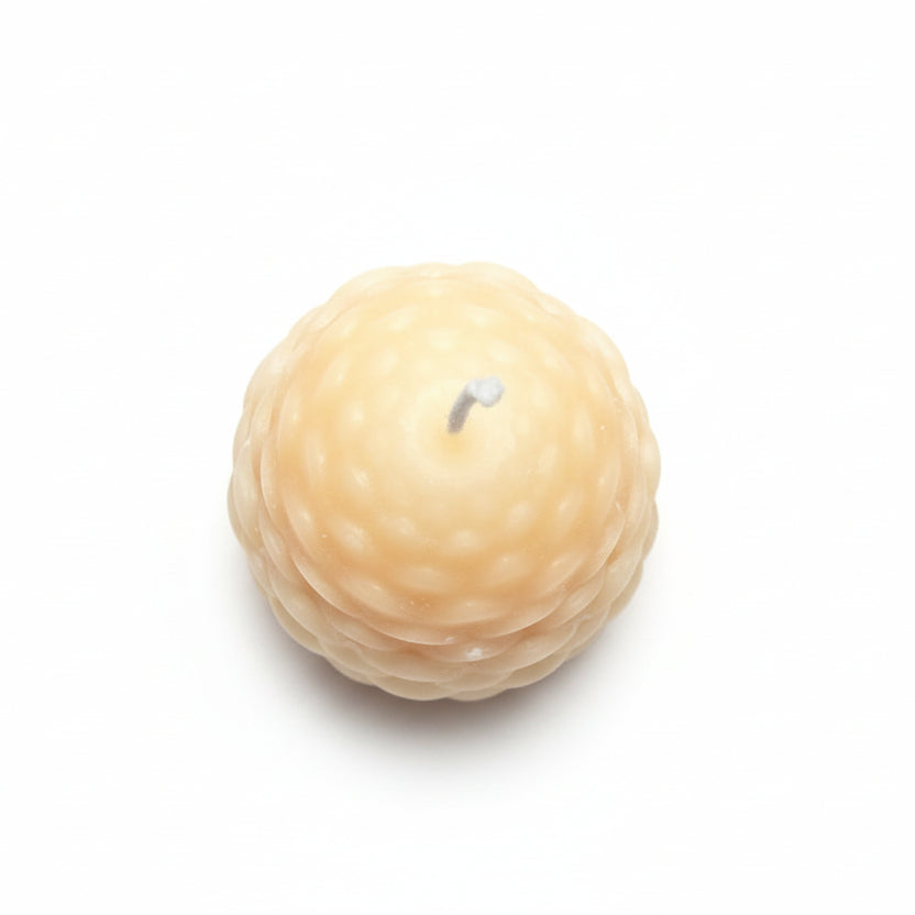 Round sculptural candle with textured wax, natural color, on white background