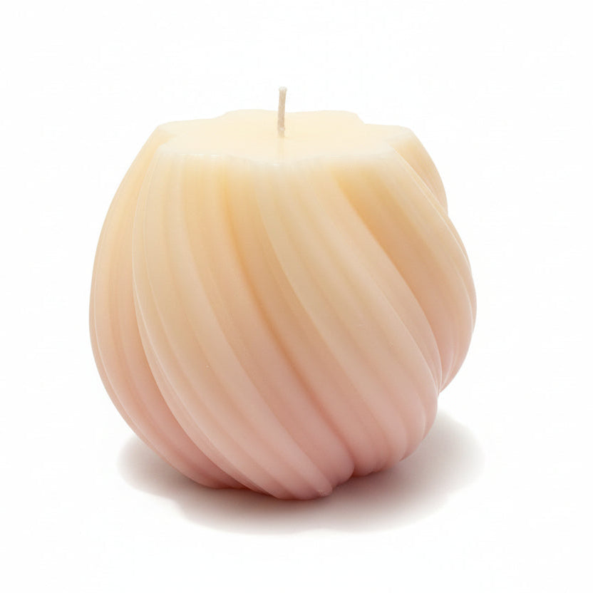 Peach-toned sculptural swirl candle with geometric design on white background