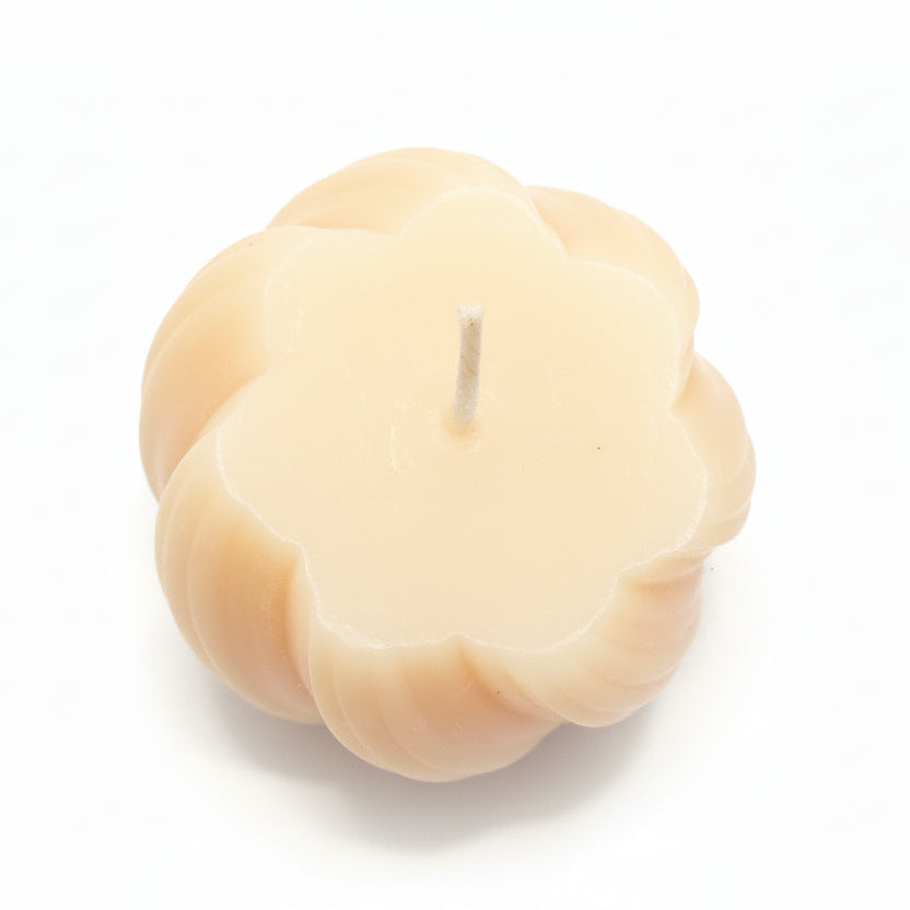 Natural wax sculptural candle with pumpkin-inspired shape on white background