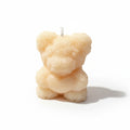 Cream-colored sculptural candle shaped like a teddy bear with floral texture on white background