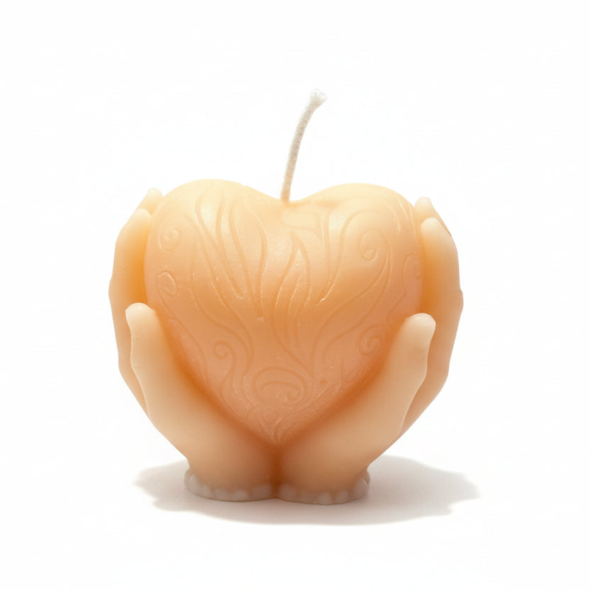Sculptural candle shaped like hands holding an embossed heart, natural wax, white background.