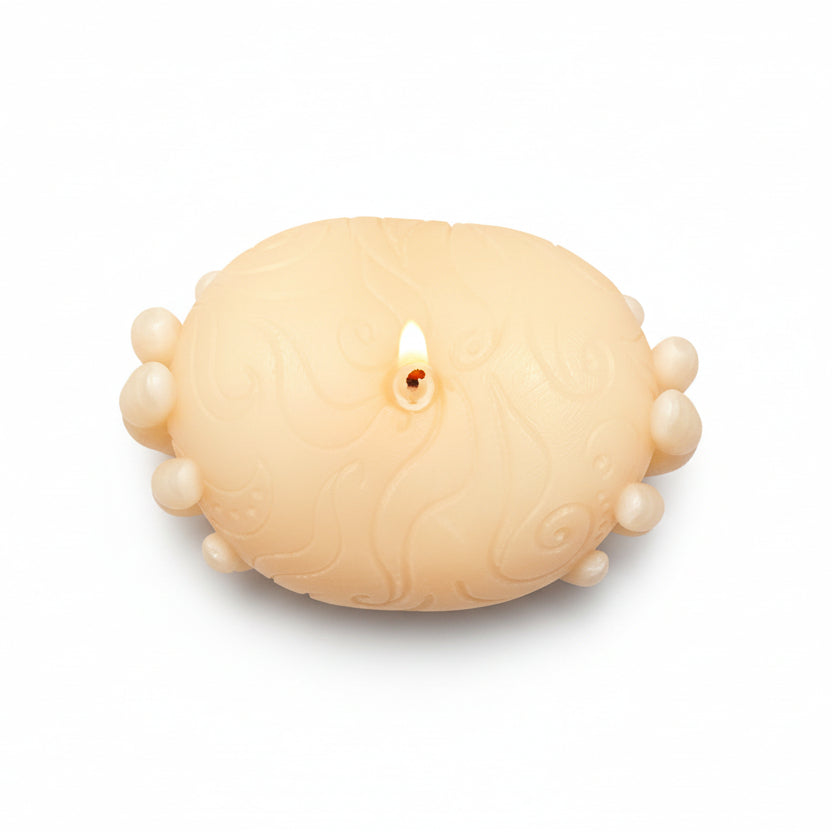 Sculptural hand-shaped natural wax candle with embossed pattern, lit on white background