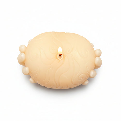 Sculptural hand-shaped natural wax candle with embossed pattern, lit on white background