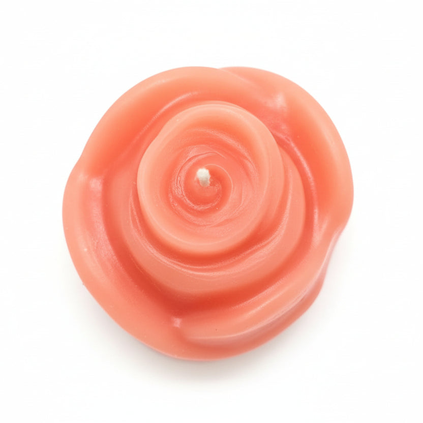 Pink rose-shaped sculptural candle made from natural wax on white background