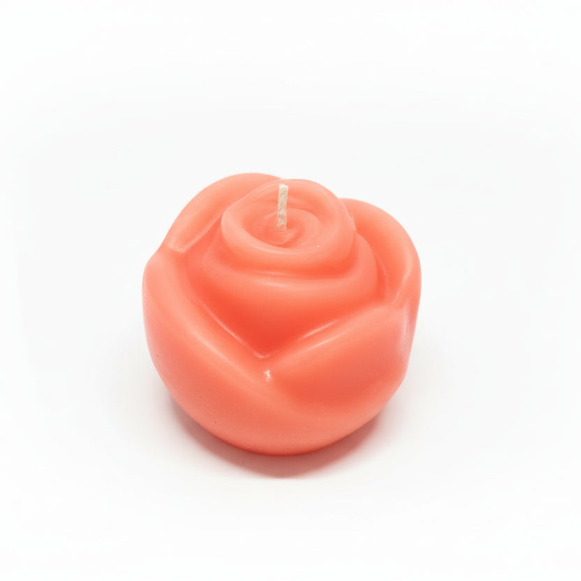Pink rose-shaped sculptural candle made from natural wax on white background