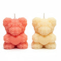 Two sculptural bear-shaped candles holding hearts, in pink and cream, with floral texture
