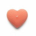 Pink heart-shaped sculptural candle with textured wax on white background
