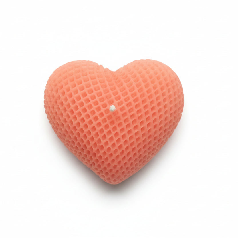 Pink heart-shaped sculptural candle with textured wax on white background