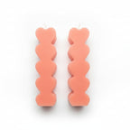 Pair of pink sculptural heart-shaped candles on white background