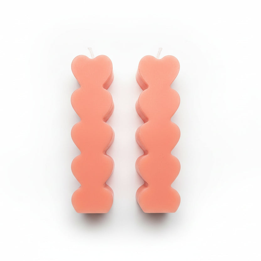 Pair of pink sculptural heart-shaped candles on white background