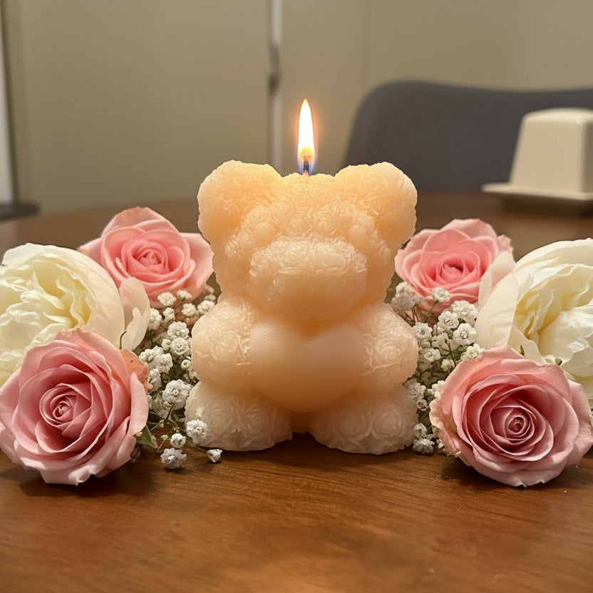 Bear-shaped sculptural candle with floral texture, surrounded by pink and white roses