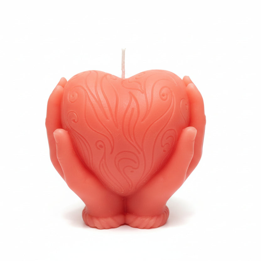 Red sculptural candle shaped like hands holding a heart with decorative patterns