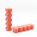 Stacked heart-shaped sculptural candles in pink natural wax on a white background