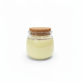 Natural wax candle in clear glass jar with cork lid on white background
