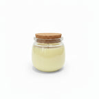 Natural wax candle in clear glass jar with cork lid on white background