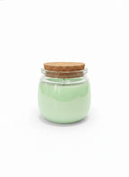 Mint green candle in clear glass jar with cork lid on white background
