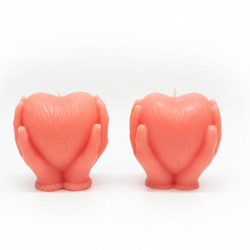 Pink sculptural candles shaped like hands holding a heart, decorative natural wax design